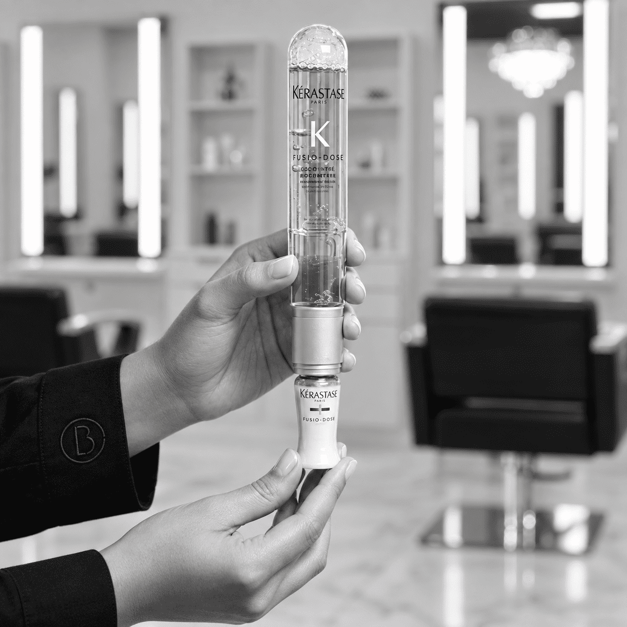 Hands holding Kérastase Fusio-Dose hair product in a modern salon setting.